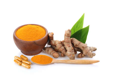 Turmeric , turmeric powder in wooden cup with wooden spoon and turmeric capsules on white...