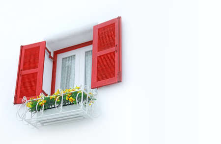 outer opened red and white inner closed window with white wall decorated with flowerpodの写真素材