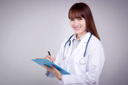 Healthy concept : Young Asian doctor writing on clipboard  for patient chartの写真素材