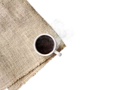 A cup of black coffee with smoke on sackcloth napkin, isolated on white background.の写真素材