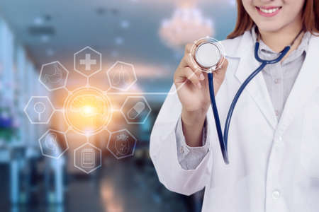 Healthy technology concept : Young Asian woman doctor holding stethoscope with hologram graphic chart popup from stethoscope on doctor hand for patient consultants,  anonymous faceの写真素材