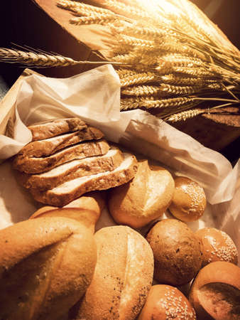 Homemade bakery concept : fresh bread and wheat on the wooden table with warm lightの写真素材