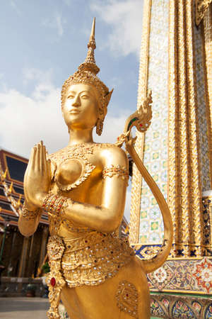 Golden Kinnari statue at Temple of Emerald Buddha (Wat Phra Kaew) in Grand Royal Palace. Kinnari is half-bird, half-woman creature at south-east Asian Buddhist mythology. Wat Phra Kaew is popular famous tourist attraction in Bangkok, landmark of Thailand,の写真素材