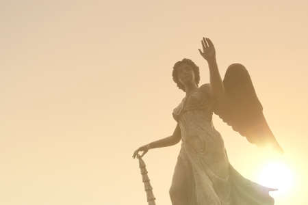 Beautiful angel statue in sunlight before sunset, faith and religion conceptの写真素材