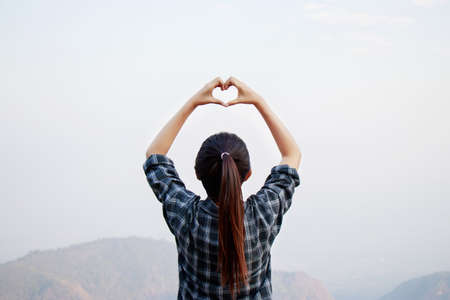 I love travel concept : Freedom traveler woman standing with heart shaped hands and enjoy a wonderful natureの写真素材