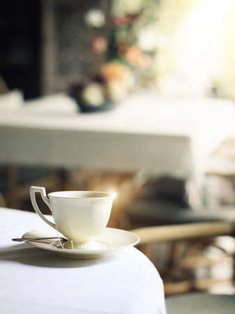 cup of hot steam coffee on table in cafe with morning glistening light reflectの写真素材