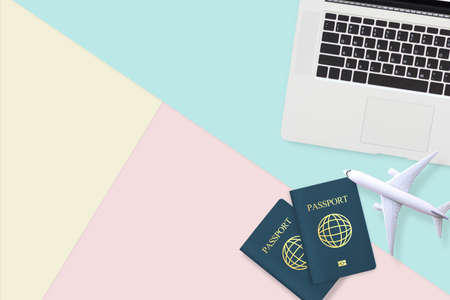 Flat lay of passport , white plane model and computer laptop on pastel blue, yellow and pink color background with copy space. travel , visa and vacation conceptの写真素材
