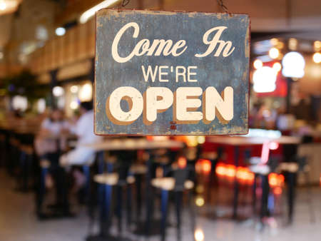 A business vintage sign that says 'Come in We're Open' on Cafe / Restaurant window. Image of...
