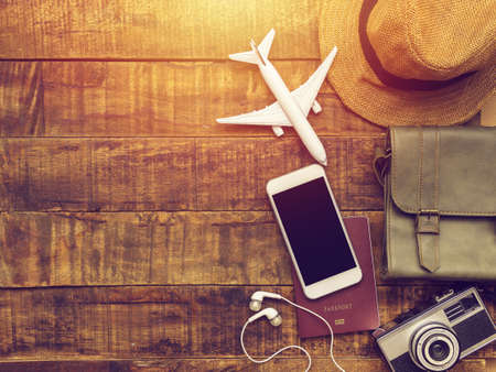 flat lay of passport , mobile , plane model , camera , bag and hat as traveler's accessories items on wooden background with copy space. travel and vacation on tropical summer season concept. vintageの写真素材