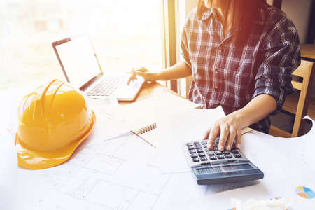 Asian engineer , architect woman using calculator for accounting and analyzing building structure...