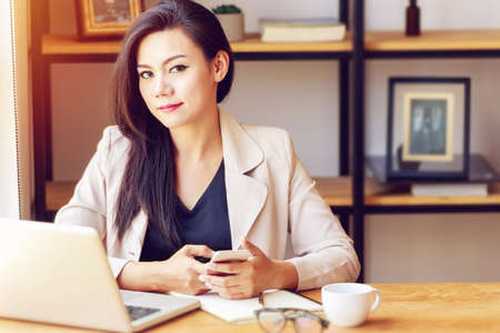 portrait of beautiful and confident Asian business woman in working age using computer laptop...