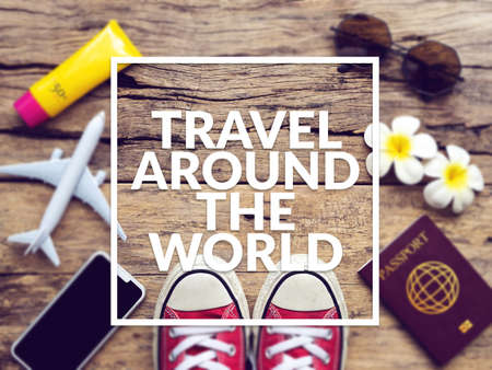 flat lay of passport , mobile , plane model , red sneakers and traveler's accessories items on wooden background with text travel around the world. travel and vacation conceptの写真素材