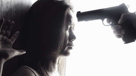 man use handgun aim on women's heads for intimidate. stop domestic violence against women campaign. reform gun control conceptの写真素材