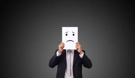 businessman wearing suit with drawing facial expressions emotions feelings on white paperの写真素材