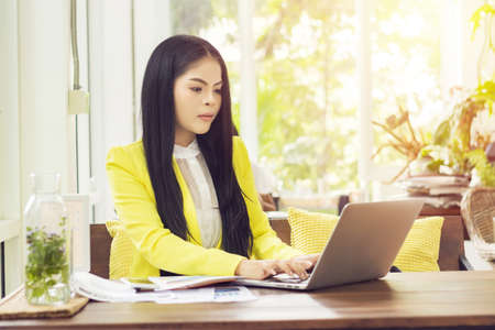 young beautiful Asian businesswoman sitting at table in coffee shop working with laptopの写真素材