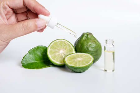 bergamot serum, organic products made from natural concept. woman hand holding glass dropper for dermatologist testing decorate with slide kaffir limes ,kaffir leaf on white background.の写真素材