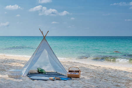 romantic white picnic tent on white sand beach with crystal clear water and blue sky at backgroundの写真素材
