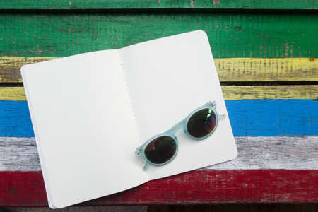 open blank white page book on colorful wooden background , decoration with sunglass fashionの写真素材