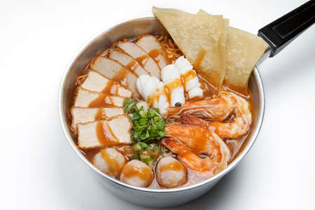 Pot of spicy instant noodles with red sauce isolated on white background. Topping with fried...