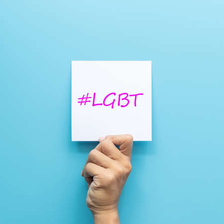 hashtag #LGBT on white paper in hand isolated on blue backgroundの写真素材