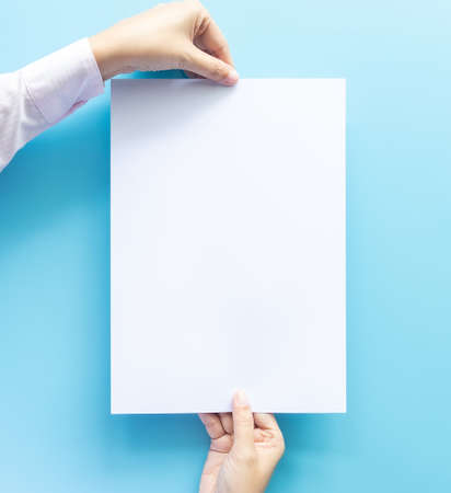 close up of two hands holding  empty white blank letter paper size A4 with copy space for flyer or...