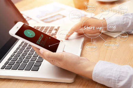 people using smart phone with startup business and rocket logo on screen and business plan management mind map, start up ideas and strategy businessの写真素材