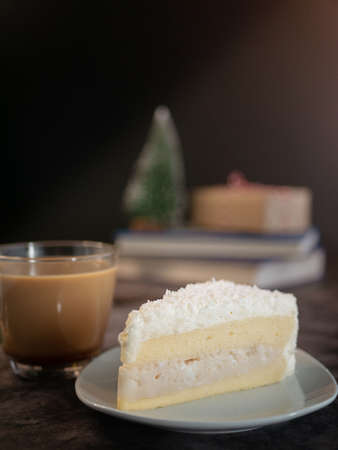 white chocolate cake with coconut cream filling served on white plate with a cup of coffee on the...