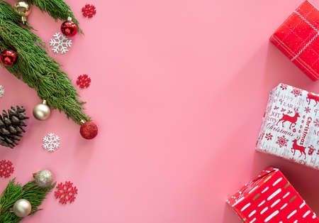 green pine, pine cone, snowflakes, Christmas ornaments and gift box in red wrap paper on pink background with copy spaceの写真素材