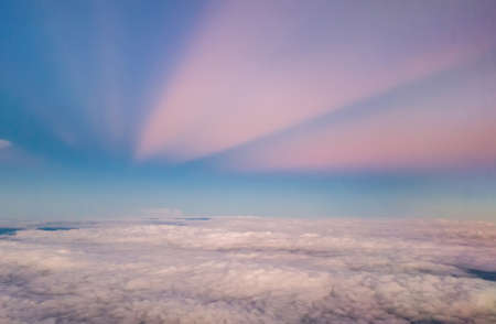 beautiful pastel sky atmosphere over white puffy cloud before sunset as seen through window of airplane, plane window. travel by airplaneの写真素材