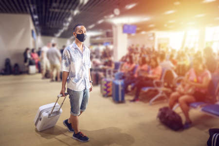 Asian tourist with luggage ,wearing mask to prevent during travel time at the airport terminal for protect from the new Coronavirus 2019 infection outbreak situationの写真素材