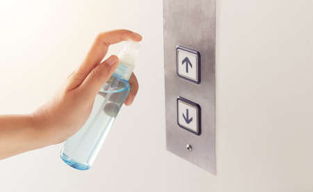 disinfect, sanitize, hygiene care. people using alcohol spray on elevator button and frequently...