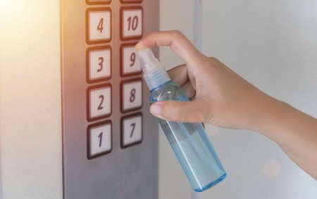 disinfect, sanitize, hygiene care. people using alcohol spray on elevator button and frequently touched area for cleaning and disinfection, prevention of germs spreading during infections of COVID-19の写真素材