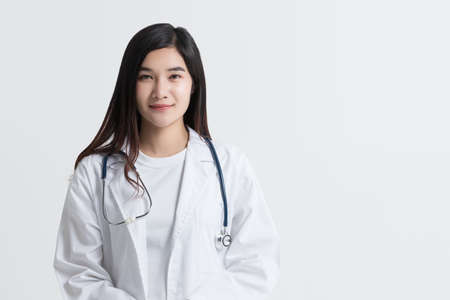 attractive Asian female doctor looking at camera with smiling face, isolated on white background with copy space. studio shotの写真素材
