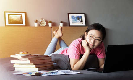 working from home, new normal concept. woman working with laptop computer on bed from her room...
