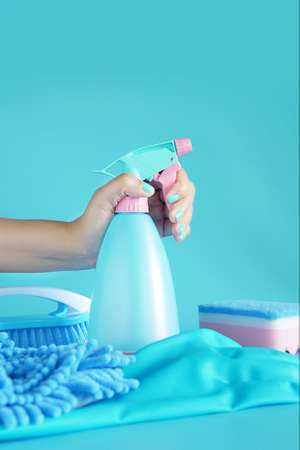 woman hand holding cleaning spray blue plastic bottle detergent isolated on blue background with cleaning tools product suppliesの写真素材