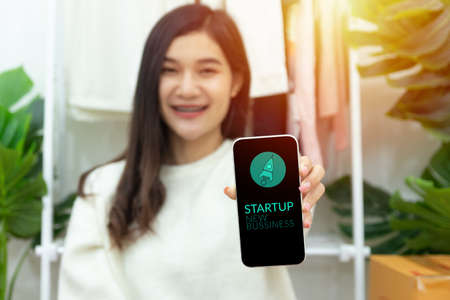 young happy confident small business owner Asian woman showing smartphone with screen display for...