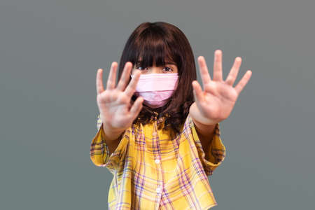 little girl wearing protective mask against transmissible infectious diseases and protection against Coronavirus Covid-19, show stop hands gesture for stop corona virus outbreak. new normal conceptの写真素材