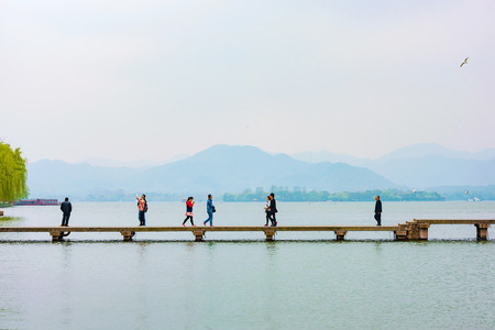 HANGZHOU, CHINA - MARCH 23: Chinese people walking along a path on Hangzhou West lake in the afternoon on March 23, in Hangzhou.のeditorial素材