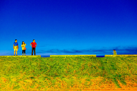 TAICHUNG, TAIWAN - AUGUST 23: Three taiwanese people standing on walkway of Gaomei wetlands which is a famous wetlands area in Taichung at night on August 23, 2014 in Taiwanのeditorial素材