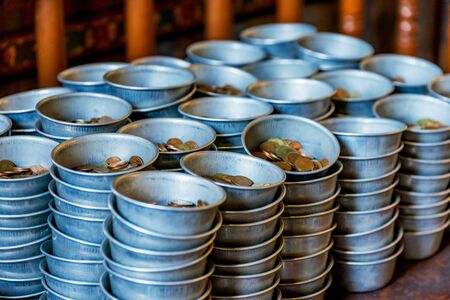 Coins in donation bowls for a buddhist temple in Thailand