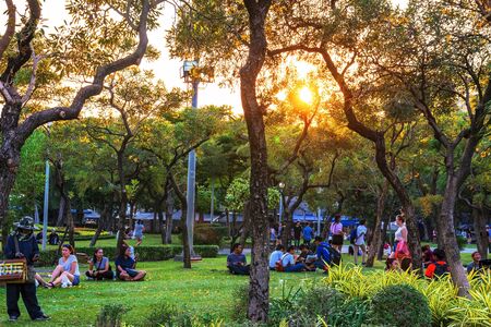BANGKOK, THAILAND - FEBRUARY 04: Chatuchak park trees and nature area with people sitting and relaxing on the grass during sunset on February 04, 2017 in Bangkokのeditorial素材