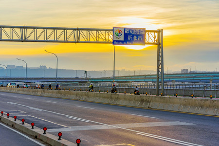 Highway on a bridge with Welcome to New Taipei city sign during sunset