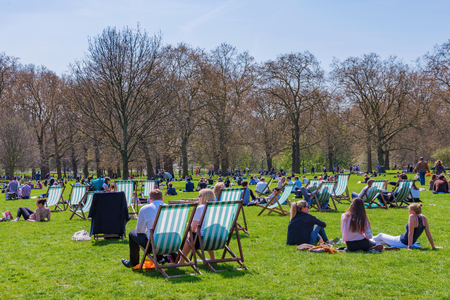 LONDON, UNITED KINGDOM - APRIL 18: People sunbathing and relaxing on a hot sunny day in Green Park on April 18, 2018 in Londonのeditorial素材