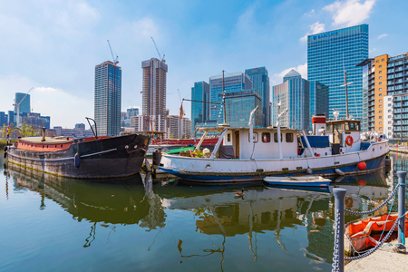 LONDON, UNITED KINGDOM - APRIL 20: View of boats and Canary Wharf financial district skyscrapers in Blackwall Basin on April 20, 2018 in Londonのeditorial素材