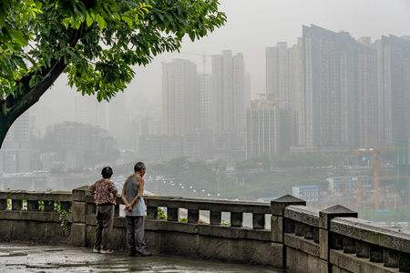 CHONGQING, CHINA - SEPTEMBER 18: Hillside viewpoint with people overlooking a foggy scene of Chongqing city on September 18, 2018 in Chongqingのeditorial素材