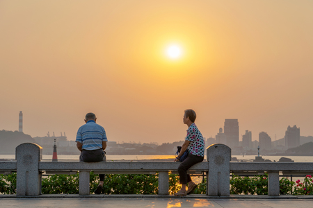 XIAMEN, CHINA -OCTOBER 08: People sitting at the waterfront promenade during sunset on October 08, 2018 in Xiamenのeditorial素材