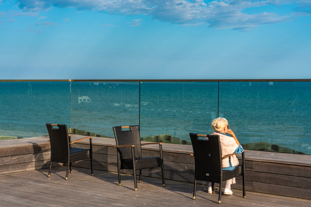 HASTINGS, UNITED KINGDOM - JULY 29: Hastings pier chairs with a person sitting and watching the sea view on July 29, 2019 in Hastingsのeditorial素材