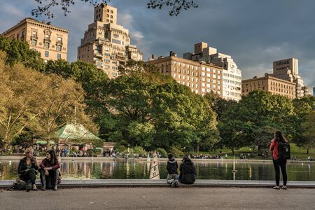 NEW YORK, USA - OCTOBER 12: View of people by the Central Park Model Boat Sailing Pond, a famous landmark on October 12, 2019 in New Yorkのeditorial素材