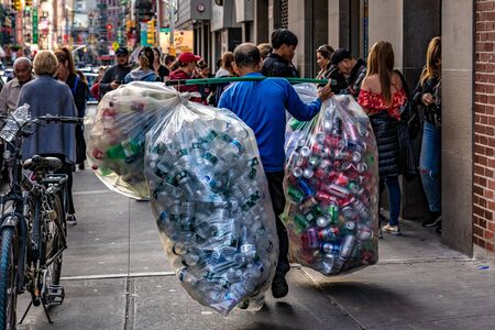 NEW YORK, USA - OCTOBER 13: This is a street scene of a man carrying bags of bottles to bring to...