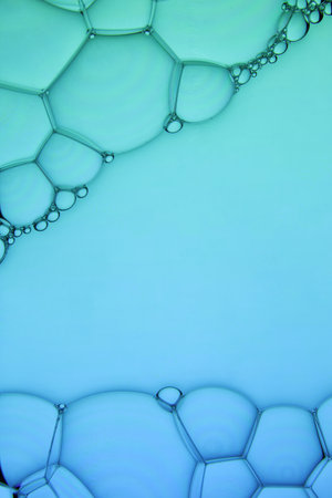 The surface of the bubbles. Extreme close-up of soap foam structure on green and blue. Cosmetic background with copy spaceの写真素材